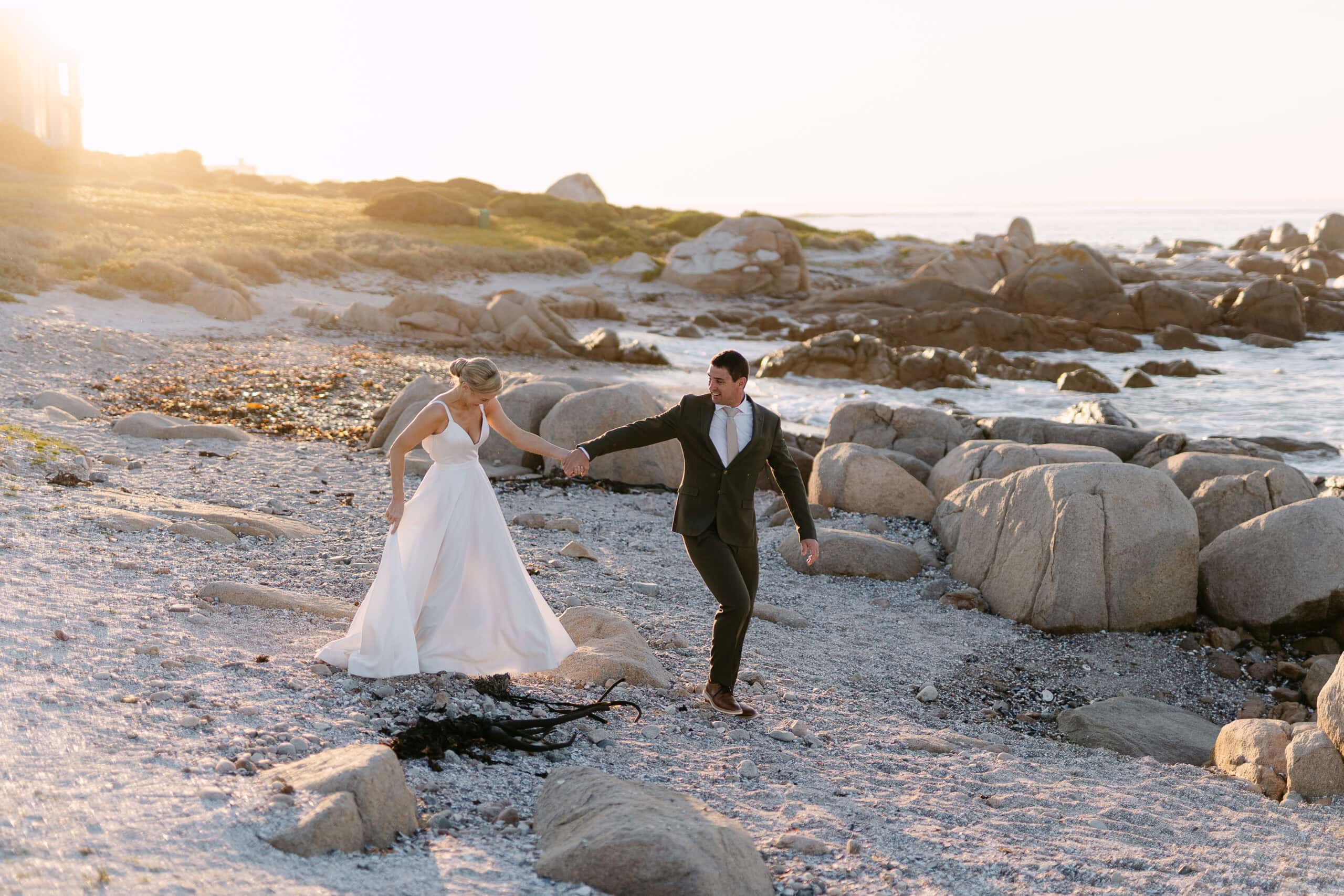 Couple running hand in hand across a rocky beach